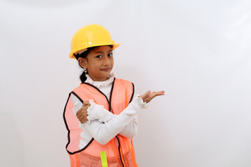 Happy Asian little girl in the construction helmet as an engineer standing while presenting sideways. Isolated on white with copyspace