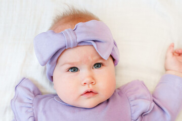 Portrait of a charming little girl toddler in a dress lying on a white sheet