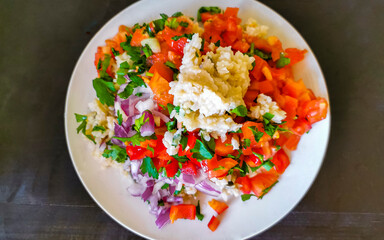 Vegetable dish with tomatoes rice onions beans on white plate.