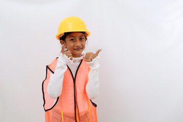 Cheerful Asian little girl in the construction helmet as an engineer standing while showing thumbs up. Isolated on white with copyspace