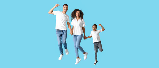 Happy jumping interracial family on light blue background