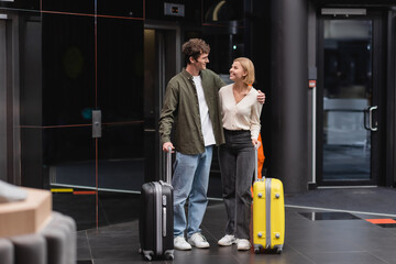 full length of young and happy couple smiling at each other near luggage in hotel lobby. © LIGHTFIELD STUDIOS
