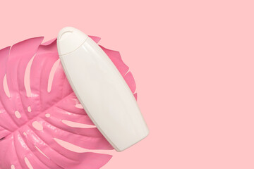 Plastic white shampoo and pink palm leaf. Hair care. On a pink background.