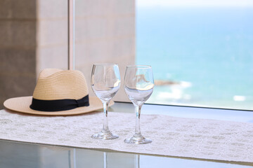 Table with wine glasses and summer hat on balcony, closeup