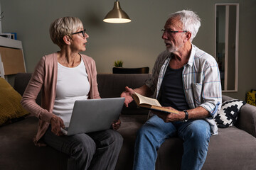 Senior couple sitting on sofa and arguing about something.