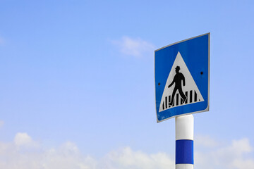 Pedestrian crossing sign against blue sky, closeup