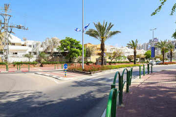 View of city street with Israel flags, palm trees and road