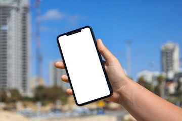 Woman with blank mobile phone in city, closeup