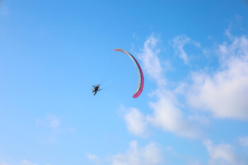 Parachutist flying in blue sky