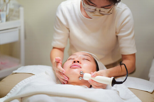 Crop beautician doing microcurrent therapy