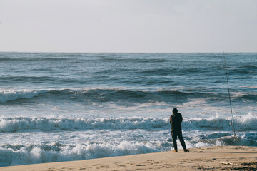 Fisherman standing at the seashore cast the fishing rod. Spin Fishing hobby catching a fish at the...