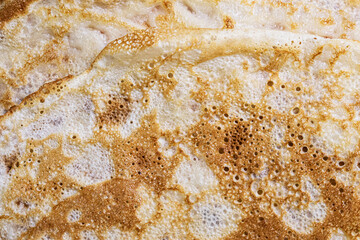 Pancake surface texture and pattern. Close-up of thin hot pancakes in a plate. Traditional rustic food. Graphic resource.
