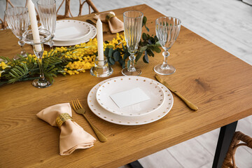 Beautiful table setting with mimosa flowers and candles in room