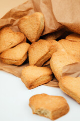 Shortbread cookies in the form of hearts in a brown paper bag on a white table. Top view