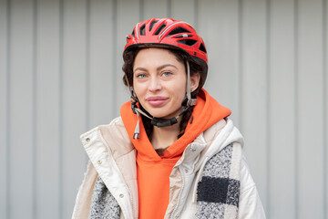 portrait of a 25-30-year-old woman in a bicycle helmet on a neutral background of garage doors.