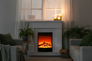 Modern fireplace with burning candles and frame in dark living room