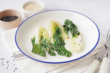 Plate of tasty stewed pak choi cabbage on light background, closeup