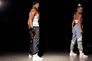 couple of man and woman dancing hip-hop in casual clothes on black background at dance hall, on...