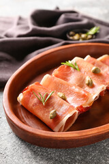 Plate with rolled slices of tasty ham on grunge background, closeup