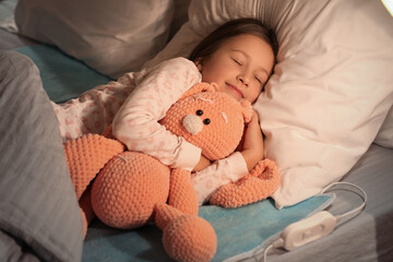 Little girl with toy sleeping on electric heating pad in bedroom at night © Pixel-Shot