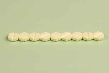 Hexagonal pills on light green background. Extreme closeup.