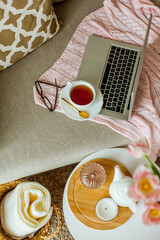 Home cozy office. Work at home. Spring decor. Knitted blanket, bouquet of tulips, hot tea, laptop. Freelance.