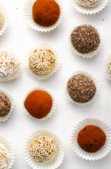 Assorted Vegan Sweets, Delicious Candy Balls with seeds, nuts and cocoa powder, Healthy Candies on Bright Background