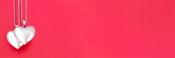Two pendants in the form of a heart on a red background, banner