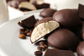 Plate with sweet chocolate bird's milk candies and coffee beans, closeup