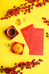 Red envelopes, cup of tea, mandarin and Chinese symbols on yellow background