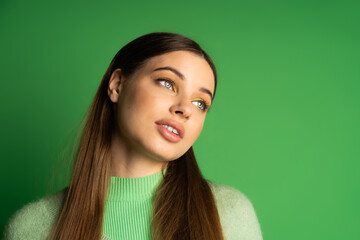 Fototapeta premium Brunette teenage girl looking away on green background.