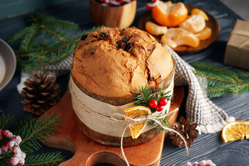 Board with tasty Panettone and Christmas decor on dark table, closeup