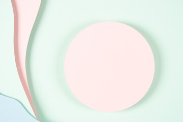 Blank pink round geometric shape podium platform on paper cut abstract geometric shape pastel pink, blue and green background. Top view mock up for product display