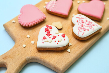 Wooden board with tasty heart shaped cookies on light background, closeup. Valentine's Day celebration