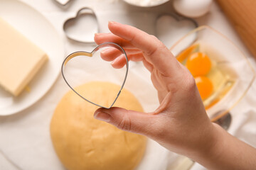 Female hand with heart shaped cookie cutter, closeup. Valentines Day celebration