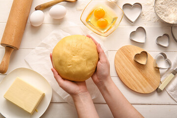 Woman preparing tasty cookies on light wooden background. Valentines Day celebration