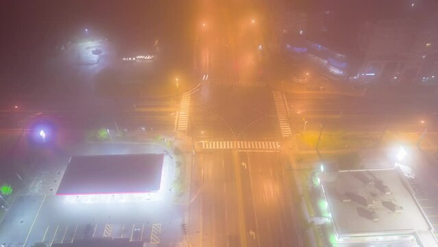 City main intersection at thick foggy night. Cinematic diffusion effect at cars transportation junction activity. Expressway view from above with night lights and illumination.