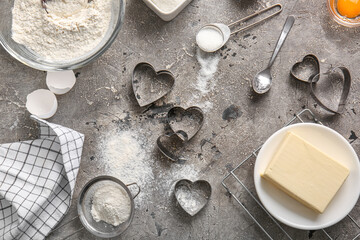 Composition with cookie cutters, flour, sugar and butter on grunge background. Valentines Day celebration