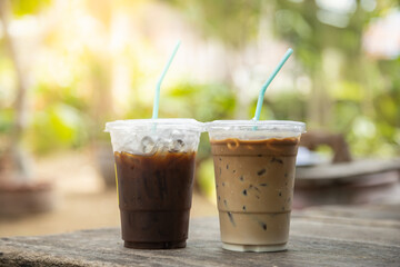 Closeup of takeaway plastic cup of iced black coffee Americano and coffee latte on wooden table...