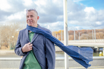 Satisfied, confident, smiling grizzled businessman with eyeglasses on head in warm jacket, scarf...