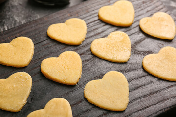 Fototapeta na wymiar Wooden board with raw heart shaped cookies, closeup. Valentines Day celebration