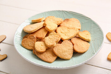 Plate with tasty heart shaped cookies on light wooden background, closeup. Valentines Day celebration