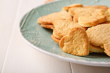 Plate with tasty heart shaped cookies on light wooden background, closeup. Valentines Day celebration