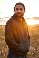 Male standing in countryside nature relaxing, having rest after training alone . caucasian guy in black sportive clothes during sunset. man lead healthy active lifestyle, stand thinking, motivated