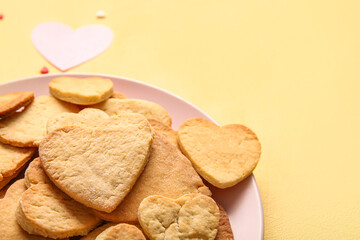 Plate with tasty heart shaped cookies on yellow background, closeup. Valentines Day celebration