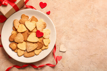 Plate with sweet heart shaped cookies and gift on color background. Valentines Day celebration