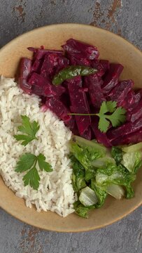 Top view of beetroot curry with sona masoori rice and stir-fried lettuce. Table spin. Vertical video.