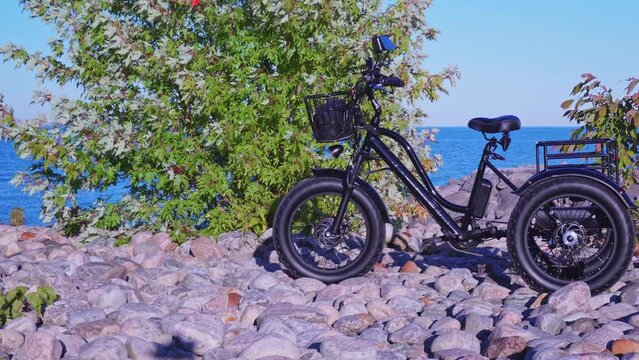 Electric bicycle in the lake park in sunny summer day. Natural lighting. Electric trike or bike E motor and power battery of the three wheel bike. Ecology and green energy concept. Ev electric vehicle