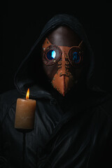 Plague doctor with crow-like mask and candle isolated on black background Creepy halloween...