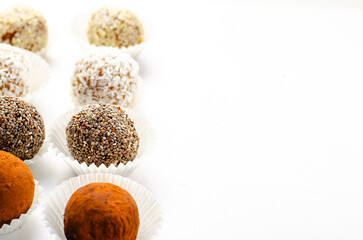 Assorted Vegan Sweets, Delicious Candy Balls with seeds, nuts and cocoa powder, Healthy Candies on Bright Background